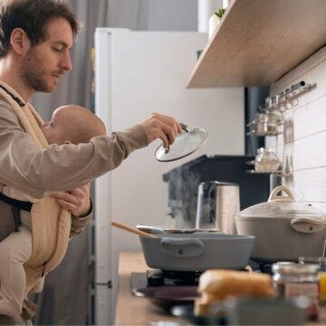 hombre cocinando con bebé en brazos sin tiempo para preparar comida saludable