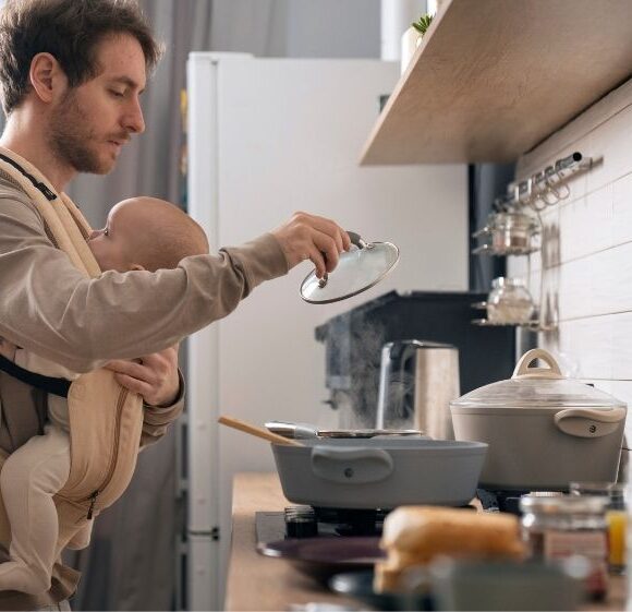 hombre cocinando con bebé en brazos sin tiempo para preparar comida saludable